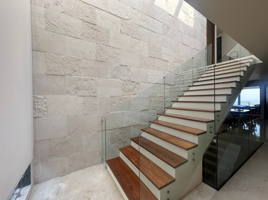 Escalera con muro de piedra y barandal de cristal
