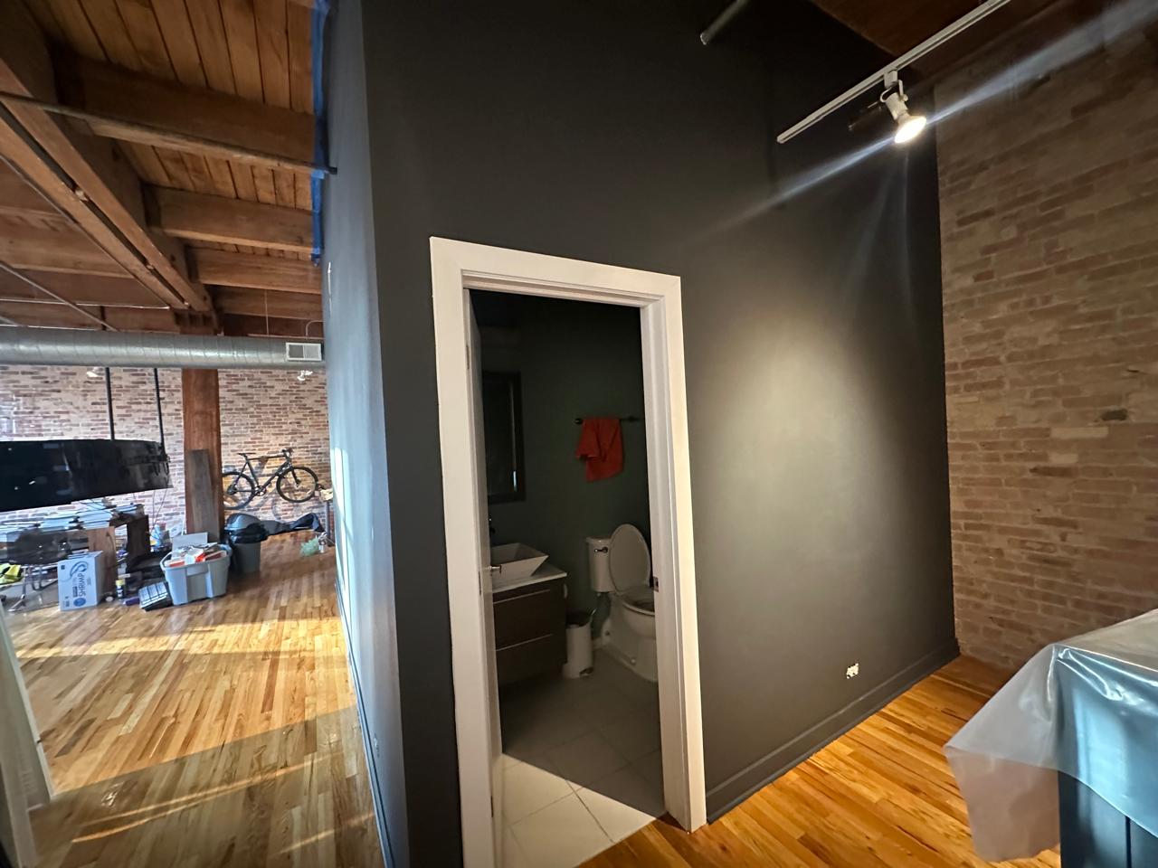 Medio baño con muro gris oscuro y ladrillo aparente