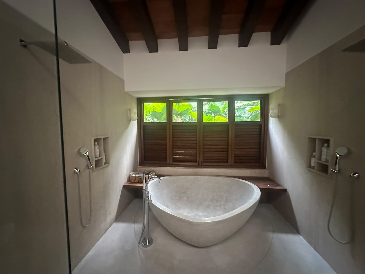 Baño con tina exenta de piedra y regaderas dobles